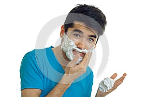 Portrait of a handsome guy with foam on his face and thick black hair on her head close-up