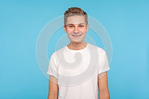 Portrait of handsome happy friendly guy in casual white t-shirt standing, smiling to camera