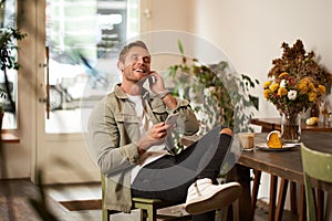 Portrait of handsome happy young man, relaxing in a coffee shop, spending time in cafe, listening to music in wireless