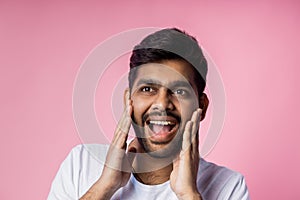 Portrait of handsome Indian guy standing on pink background