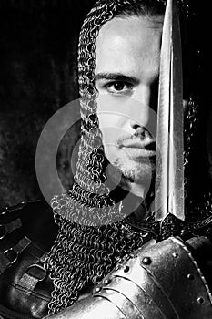 Portrait of handsome knight in suit of armour looking at camera with candles in background