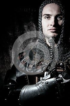 Portrait of handsome knight in suit of armour looking at camera with candles in background