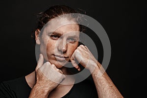 Portrait of a handsome long-haired man with drawn hair and freckles wearing a black T-shirt