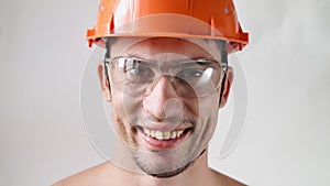 Portrait, handsome male builder in work helmet and glasses smiling at the camera