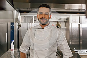 Portrait of handsome male chef in uniform standing on kitchen of restaurant