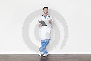 Portrait Of Handsome Male Doctor In Uniform With Clipboard In Hands