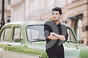 Portrait, handsome, male, model, brunette Mediterranean race Turkish man stands near a retro car of green color posing
