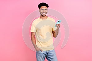 Portrait of handsome man arm in pocket hold smartphone facebook instagram whatsapp twitter telegram isolated on pink