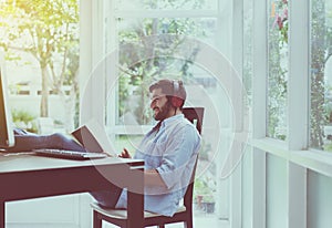 Portrait of handsome man with beard reading book and listening to music online at coworking space,Happy and smiling,Relax time