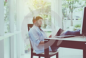 Portrait of handsome man with beard reading book and listening to music online at coworking space,Happy and smiling,Relax time