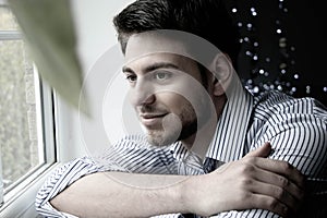 Portrait of handsome man with beard sitting next to window