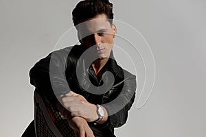 portrait of handsome man in black leather jacket holding wrists photo