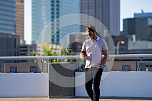 Portrait of handsome man chatting on phone outdoor. Stylish man talking on phone dressed in polo. Fashion male posing on