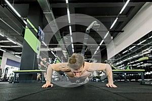 Portrait of a handsome man doing push ups exercise in fitness gym