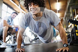 Portrait of a handsome man doing push ups exercise in gym