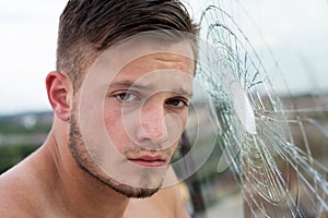 Portrait of handsome man. Gangster man. Dangerous criminal, hooligan guy on cracked bullet glass.