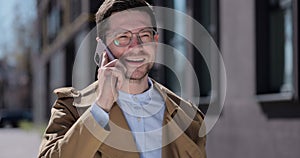 Portrait handsome man in glasses having phone talk on the street. Business man talking on smartphone at street. Outdoor