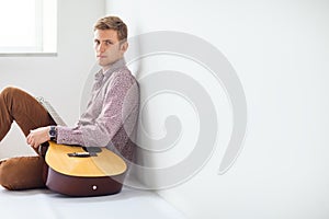 Portrait of handsome man with guitar siting on floor