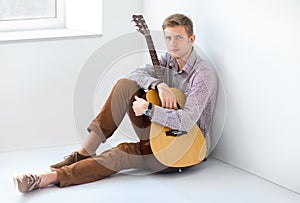 Portrait of handsome man with guitar siting on floor