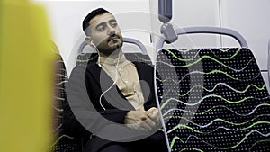 Portrait of handsome man in headphones listening to music in public transport. Media. Young man in empty bus looking