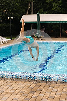 Portrait of handsome man jumping and diving into the swimming pool.