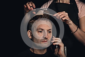 Portrait of handsome man with model haircut. New trendy modern hairstyle. Barber is shearing man hair. Middle-aged man in