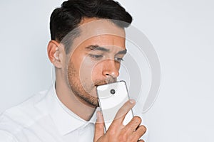 Portrait of handsome man send text on mobile phone isolated against gray background. Technology and connection idea.