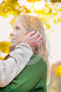 Portrait of handsome man showing affection to his wife in park with lens flare