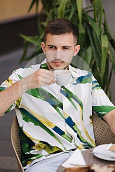 Portrait of handsome man sitting in cafe and drinking cappuccino. Young man