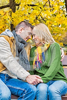 Portrait of handsome man sitting while showing affection to his beautiful wife in park