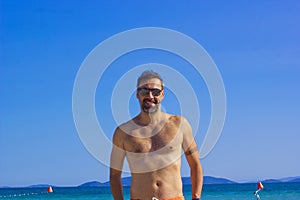 Portrait of handsome man smiling at camera on the beach in summer