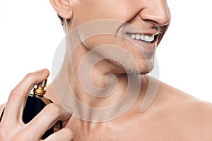 Portrait of handsome man using perfume after shower in morning isolated.