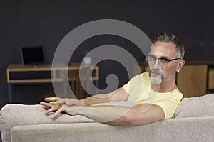 Portrait of handsome man wearing glasses at home sitting on sofa