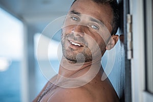 Portrait of handsome man with white teeths smile, blue eyes, surfer and blue ocean