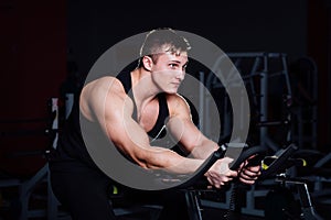 Portrait of a handsome man workout on fitness the exercise bike dark at gym.