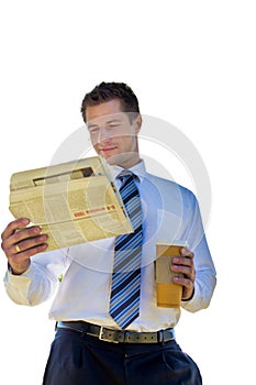 Portrait of handsome mature businessman holding cup of coffee while reading newspaper in park during break