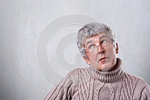 A portrait of handsome mature male wearing eyeglasses looking up with dreamy expression thinking about his life missing his childr