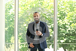 Portrait of handsome mature man in elegant suit with coffee