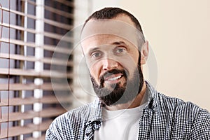 Portrait of handsome mature man near window with blinds