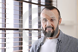 Portrait of handsome mature man near window indoors