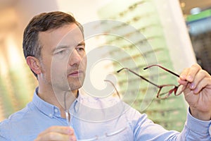Portrait handsome mature man trying new glasses at optician