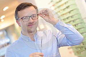 Portrait handsome mature man trying new glasses at optician