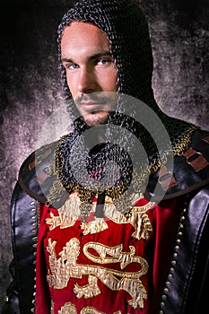 Portrait of handsome medieval knight in suit of armour with beard and blue eyes looking at camera