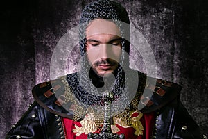 Portrait of handsome medieval knight in suit of armour with beard looking down in contemplation