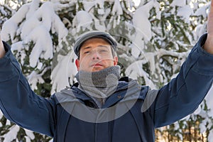 Portrait of handsome middle-aged man taking selfie against winter landscape with snow covered pine trees in sunny day. Human and