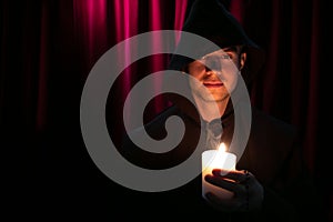 Portrait of handsome monk holding a candle and looking at camera