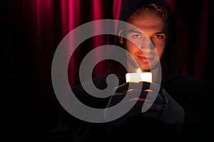 Portrait of handsome monk holding a candle and looking at camera