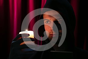 Portrait of handsome monk holding a candle and looking at camera