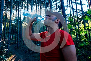 Portrait of a handsome mountain biker drinking water while wearing his baseball cap hat