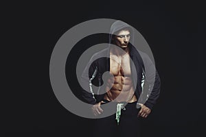 Portrait of a handsome muscular bodybuilder in hoodie posing ove